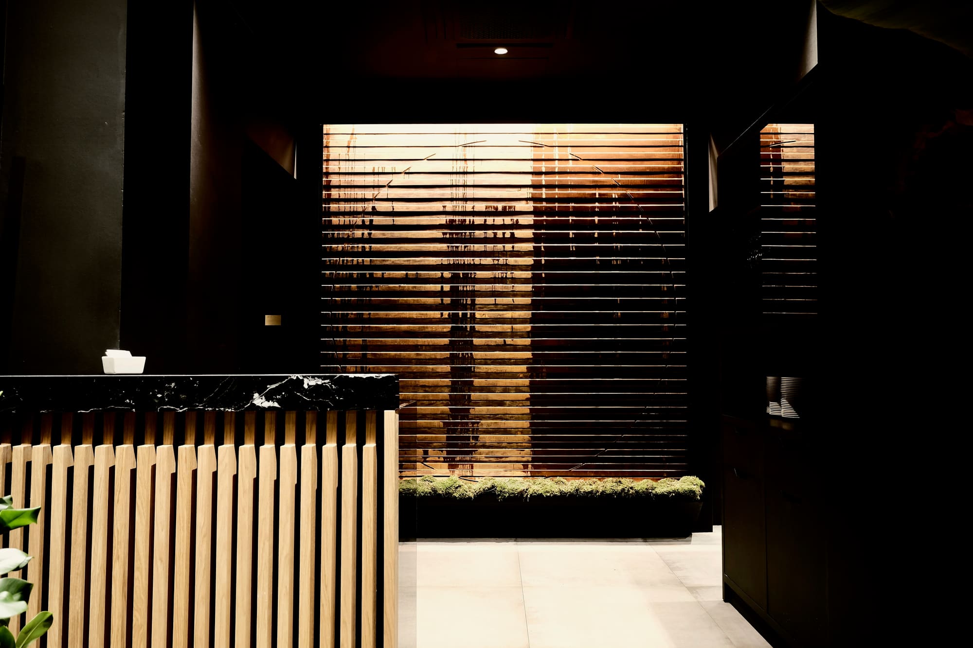 Ingresso ristorante giapponese · tendaggi in legno verticali · parete marmo nero · dettaglio Zen